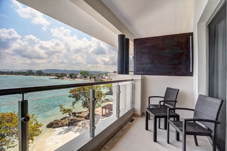 Ocean-view balcony with two chairs outside a Luxury Junior Suite at Royalton Negril.