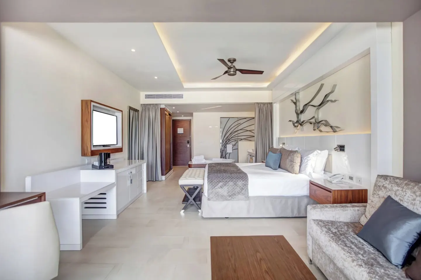 Luxury Junior Suite king bed, sofa, desk, and TV at Royalton Negril.