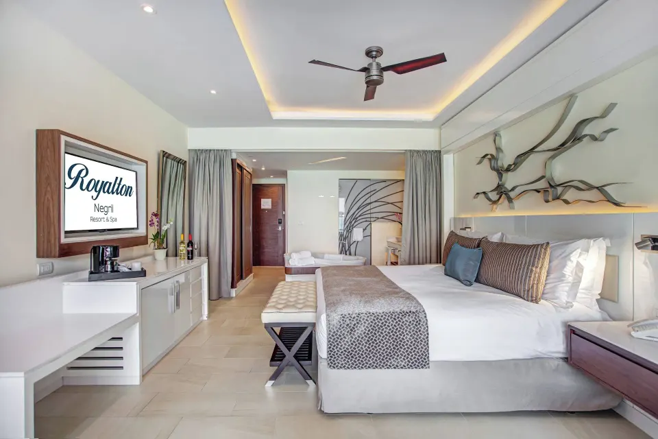 Luxury Junior Suite king bed with TV and branded screen at Royalton Negril.