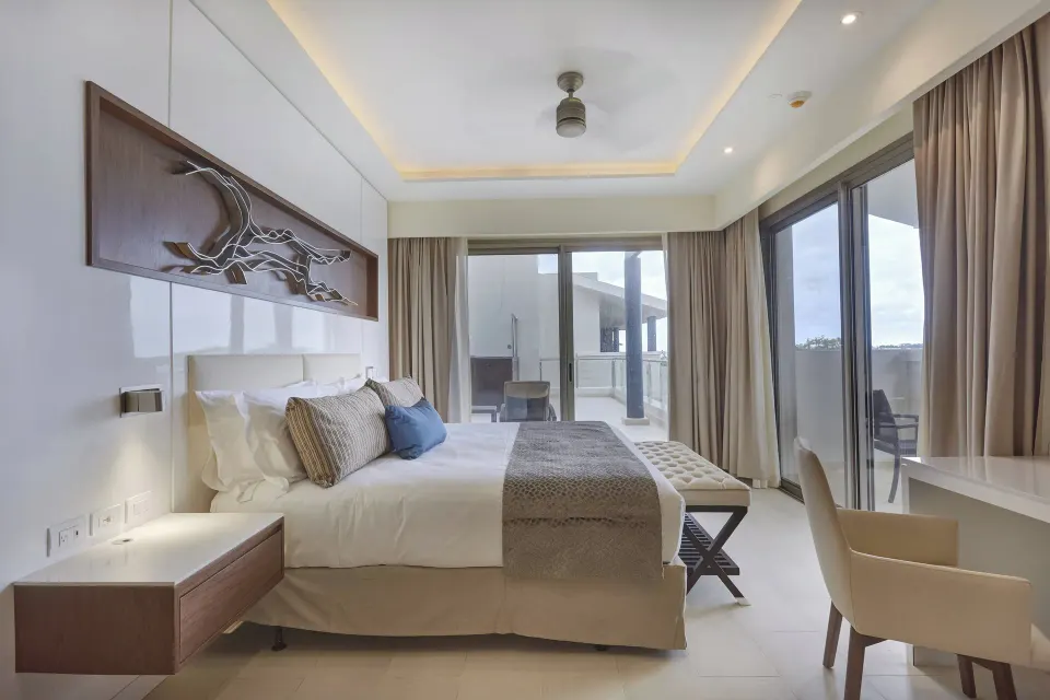 King bedroom with wall art, desk chair and terrace doors at Royalton Negril.