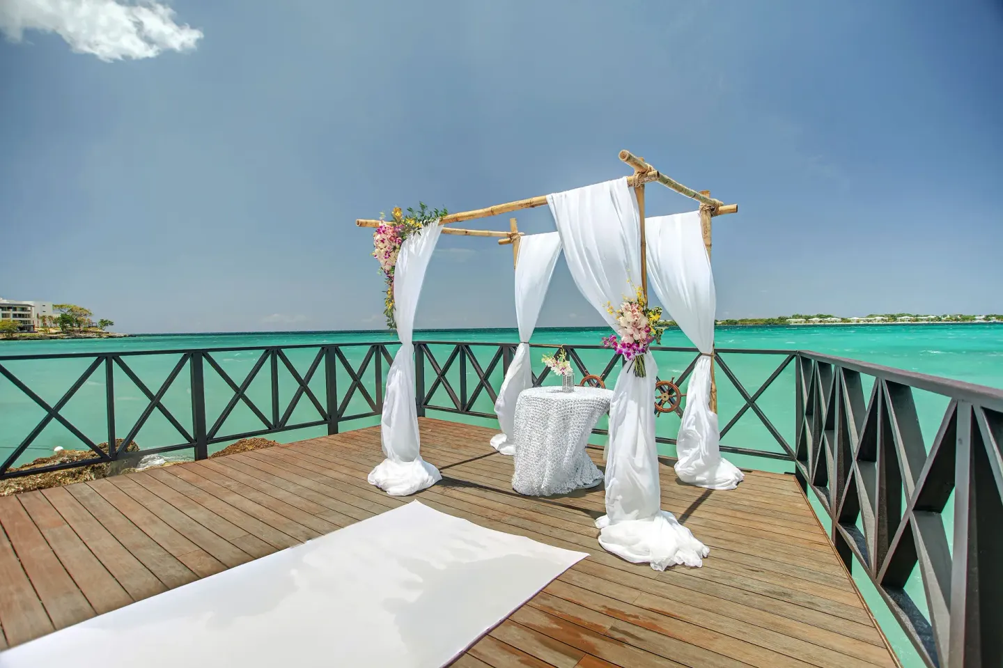 A draped wedding arch stands on an oceanfront deck at Royalton Negril.