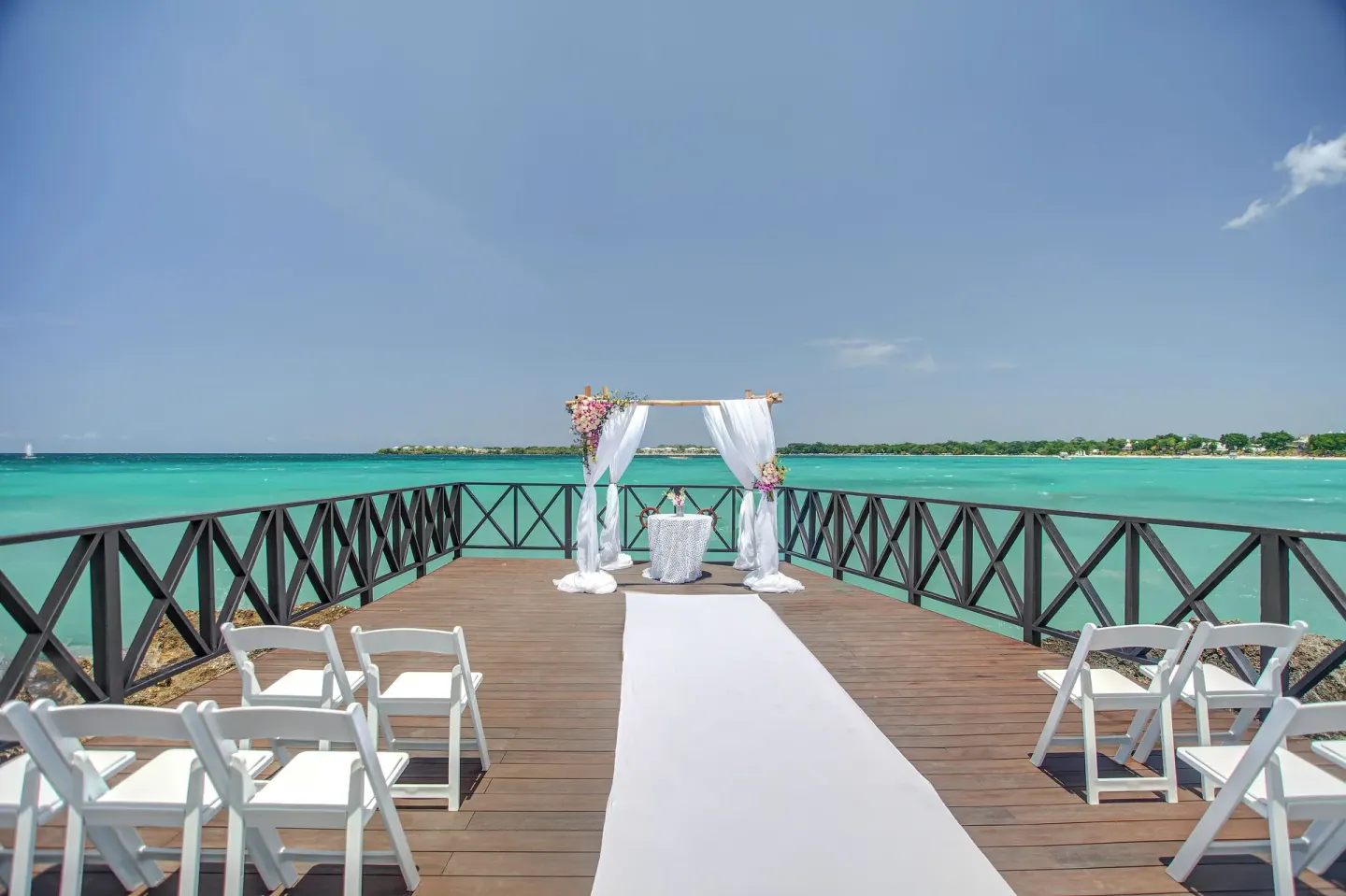 An oceanfront wedding aisle and arch are set on a pier at Royalton Negril.