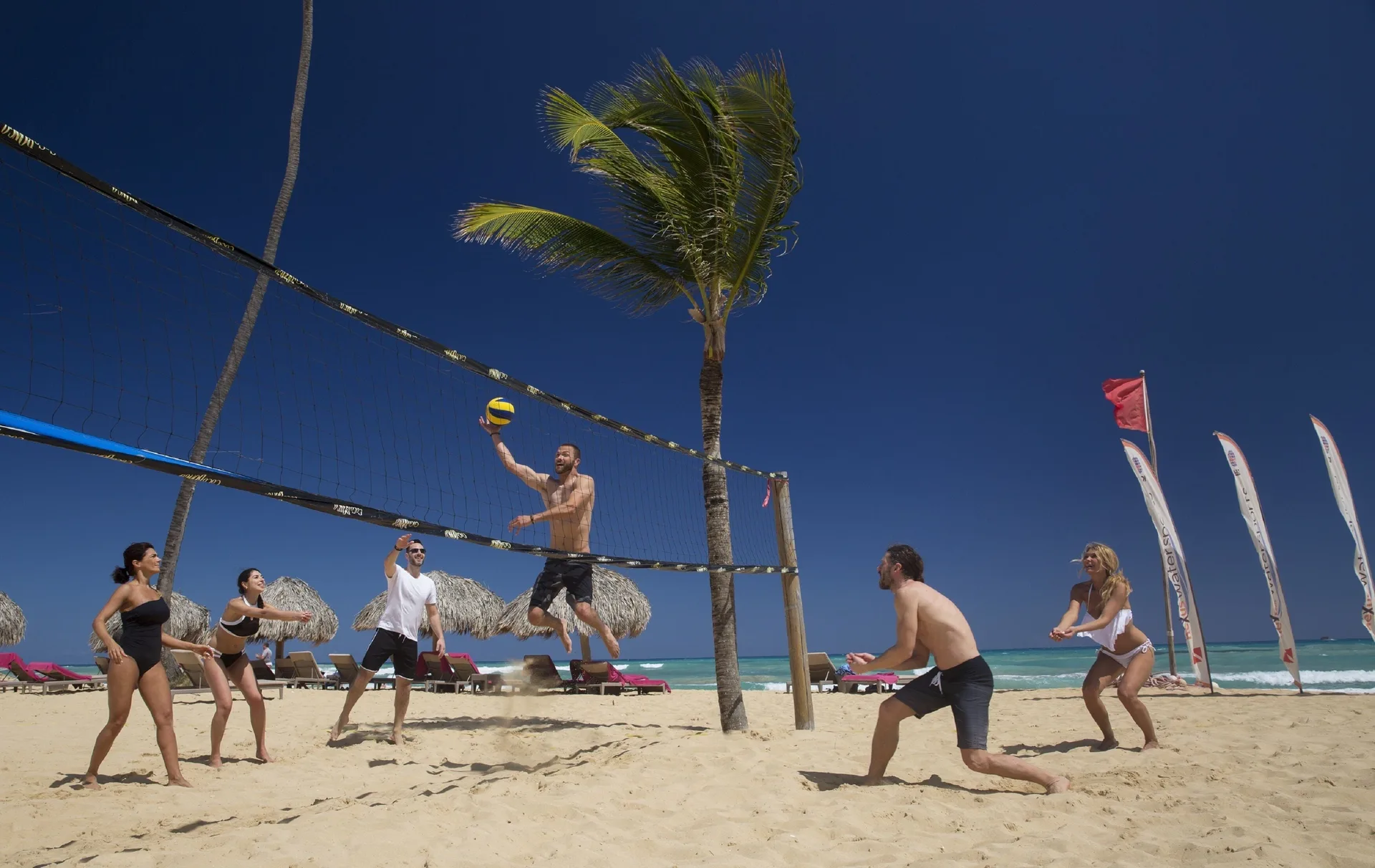 Guests playing beach volleyball beside the sea at Royalton Splash Riviera Cancun.