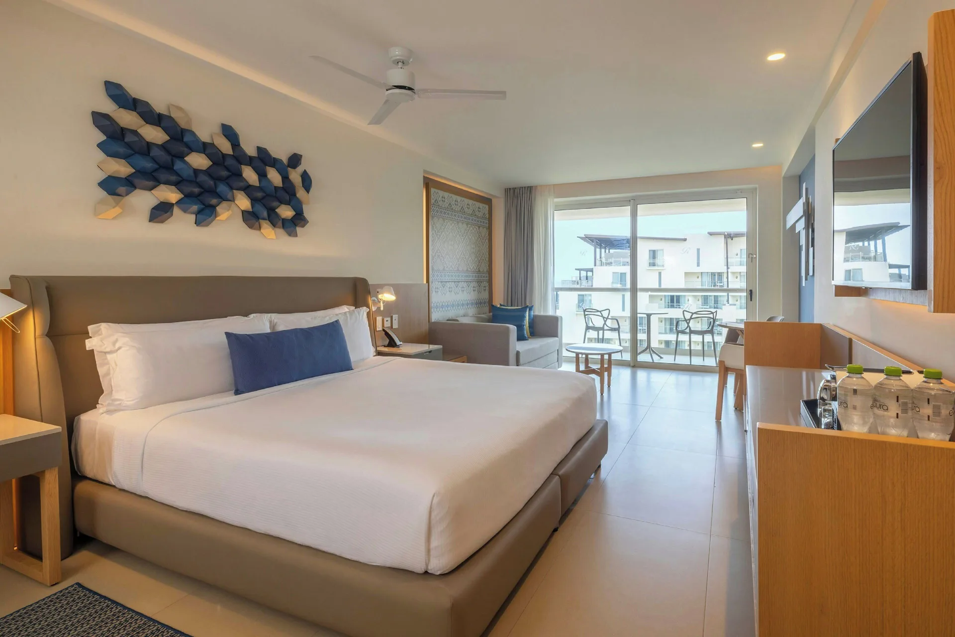 King-bed guest room with balcony doors and seating at Royalton Splash Riviera Cancun.