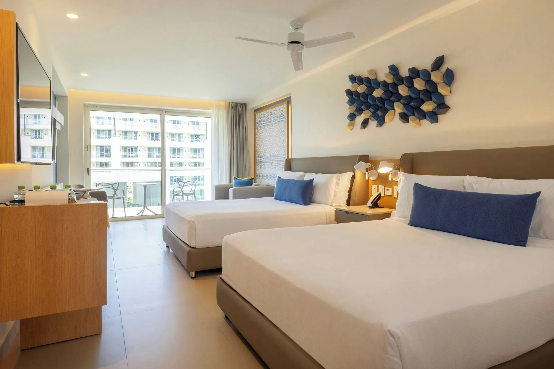 Guest room with two queen beds and balcony view of resort buildings at Royalton Splash Riviera Cancun.