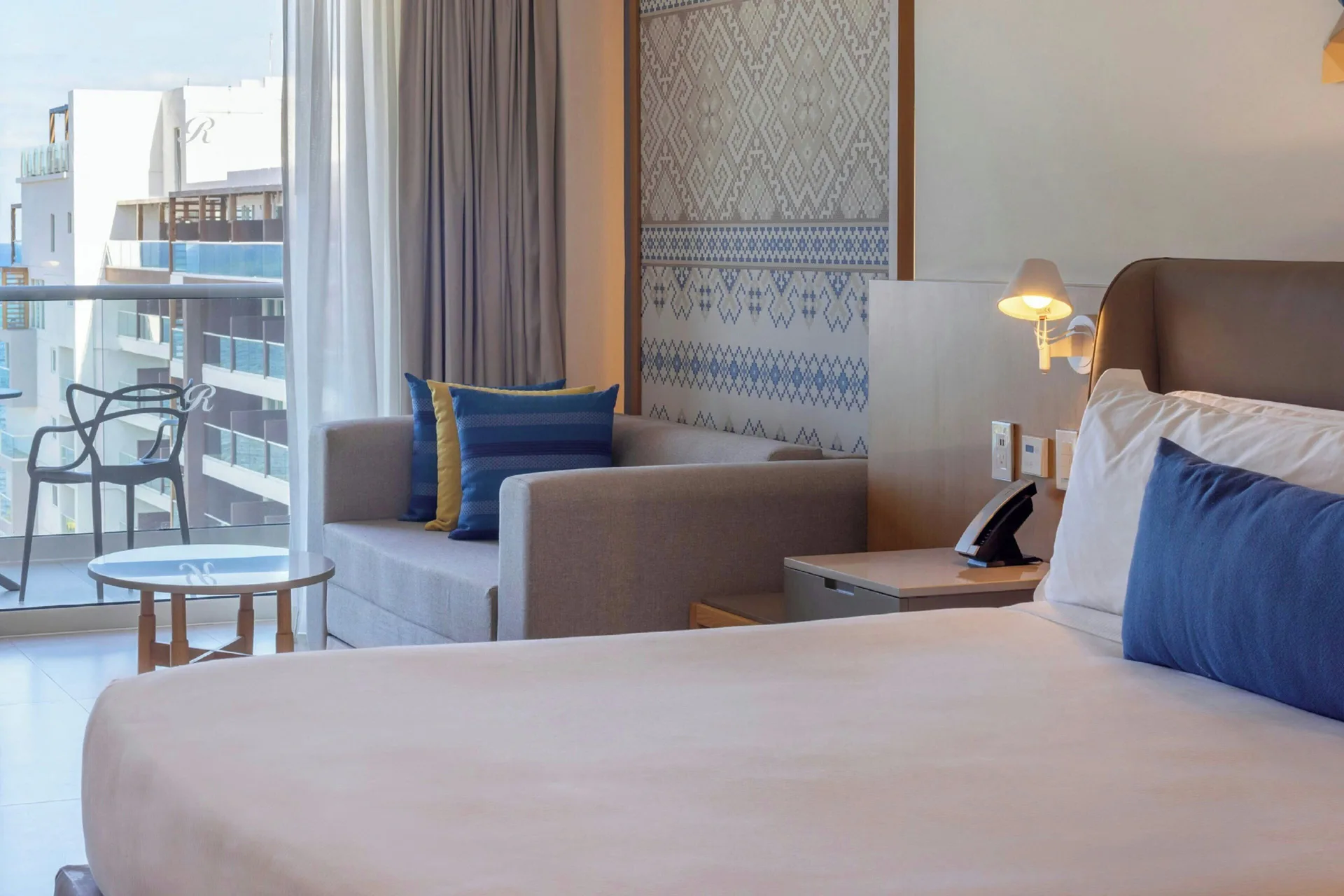 Guest room king bed with sofa and balcony at Royalton Splash Riviera Cancun.