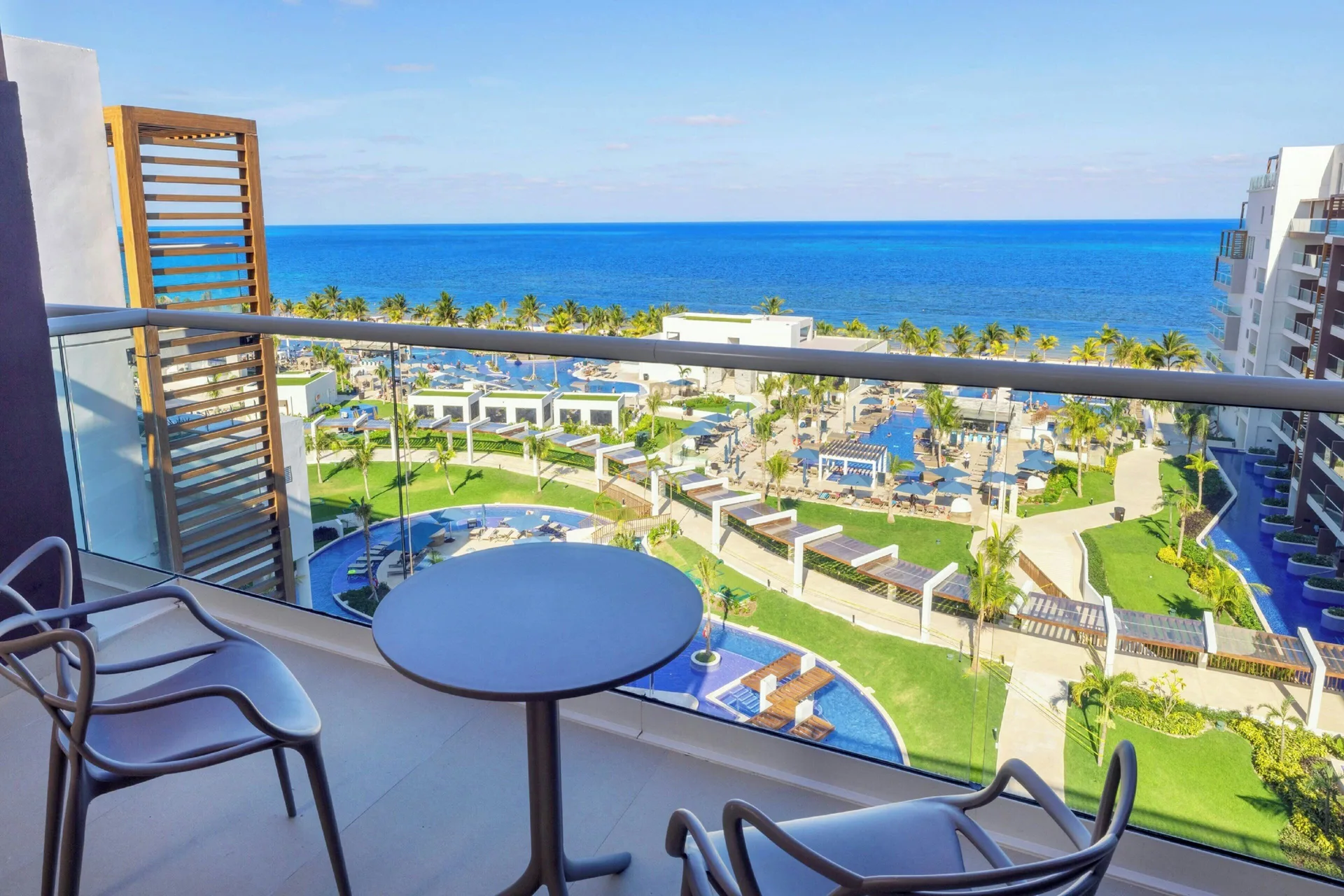 Balcony seating overlooks pools, palms and the sea at Royalton Splash Riviera Cancun.