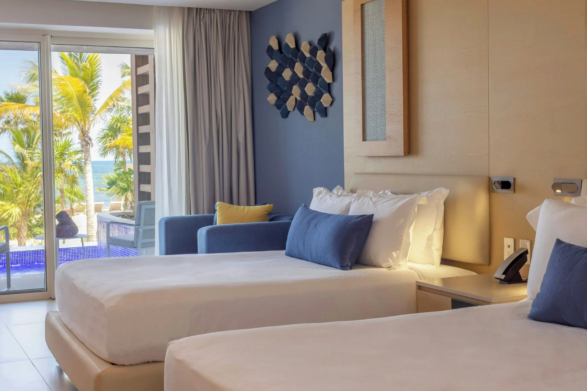 Two-bed guest room with palm and ocean view at Royalton Splash Riviera Cancun.