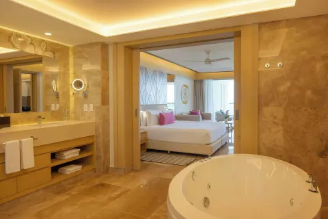 Suite bathroom with round tub and view into king bedroom at Royalton Splash Riviera Cancun.