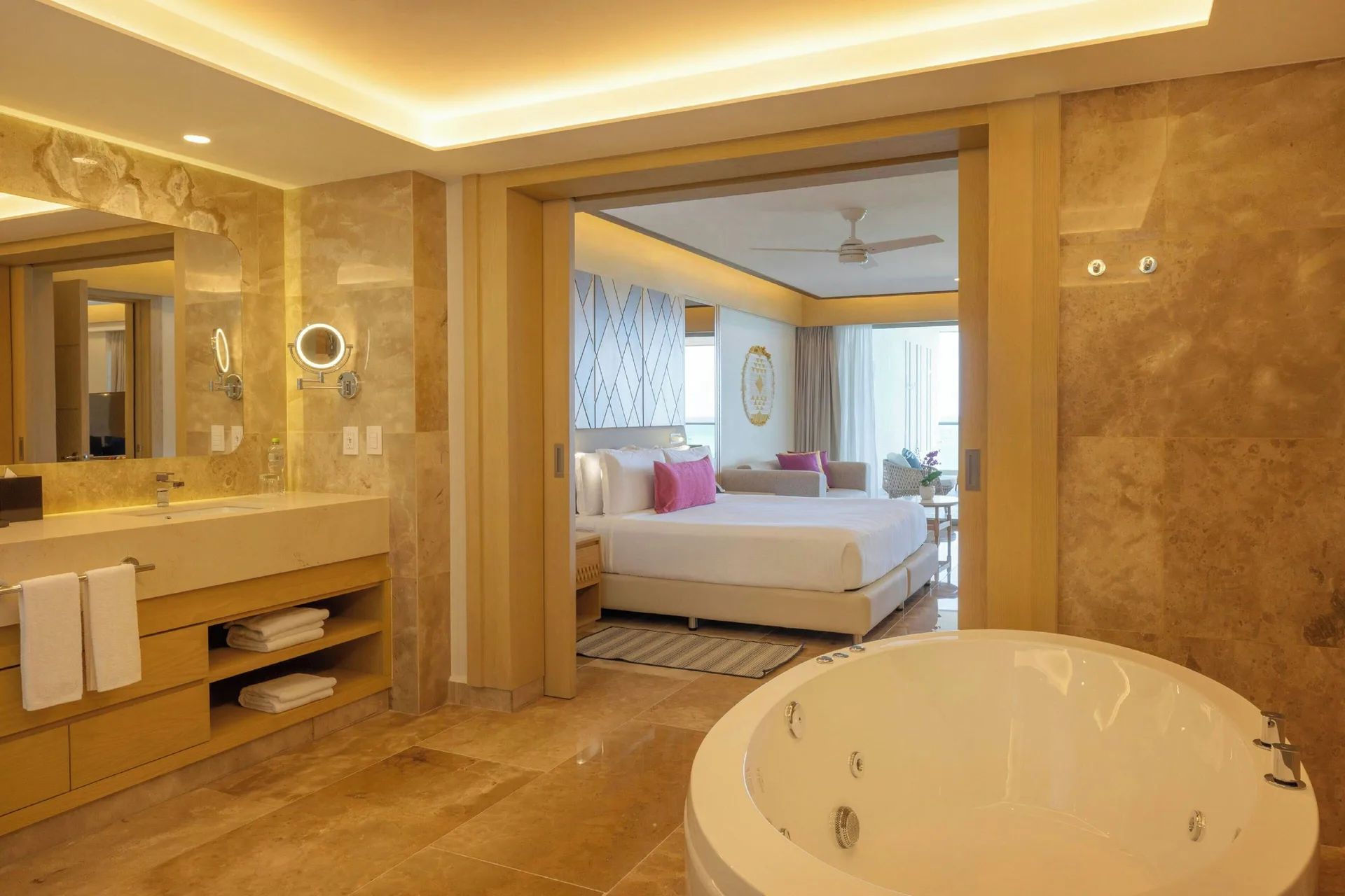 Suite bathroom with round tub and view into king bedroom at Royalton Splash Riviera Cancun.