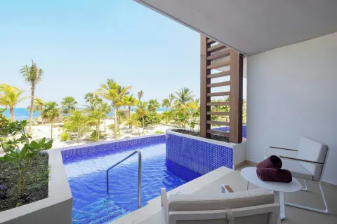 Swim-out terrace with blue pool, loungers, palms, and sea at Royalton Splash Riviera Cancun.