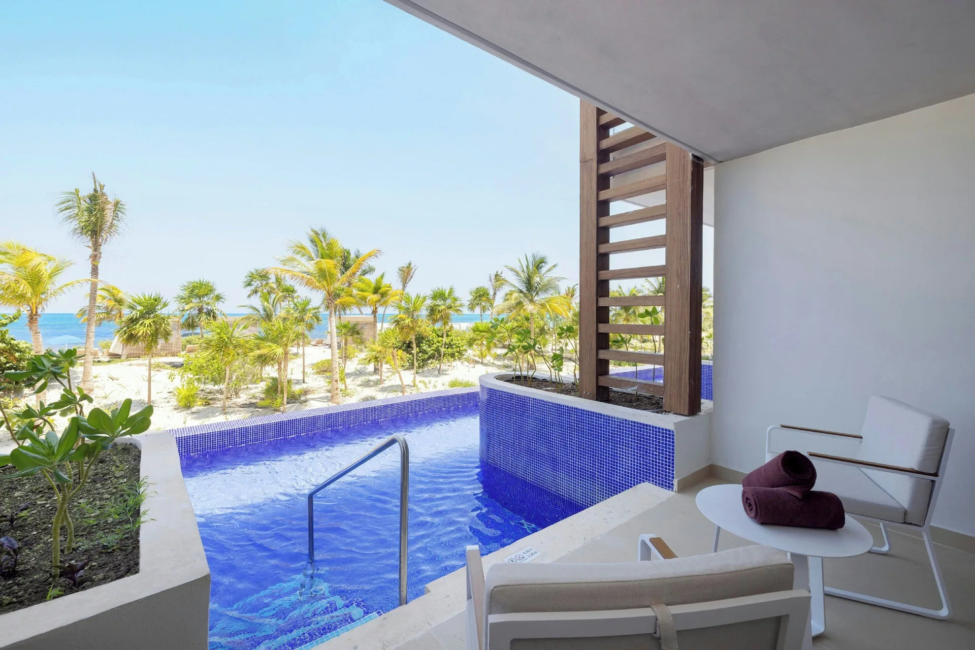 Swim-out terrace with blue pool, loungers, palms, and sea at Royalton Splash Riviera Cancun.