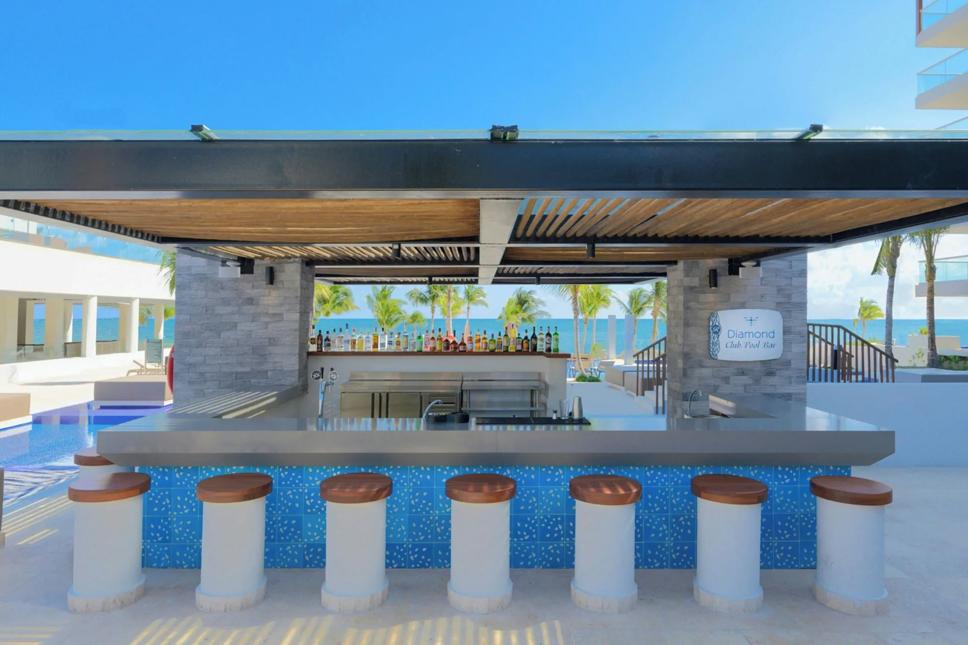 Pool bar with stools and ocean view at Royalton Splash Riviera Cancun.