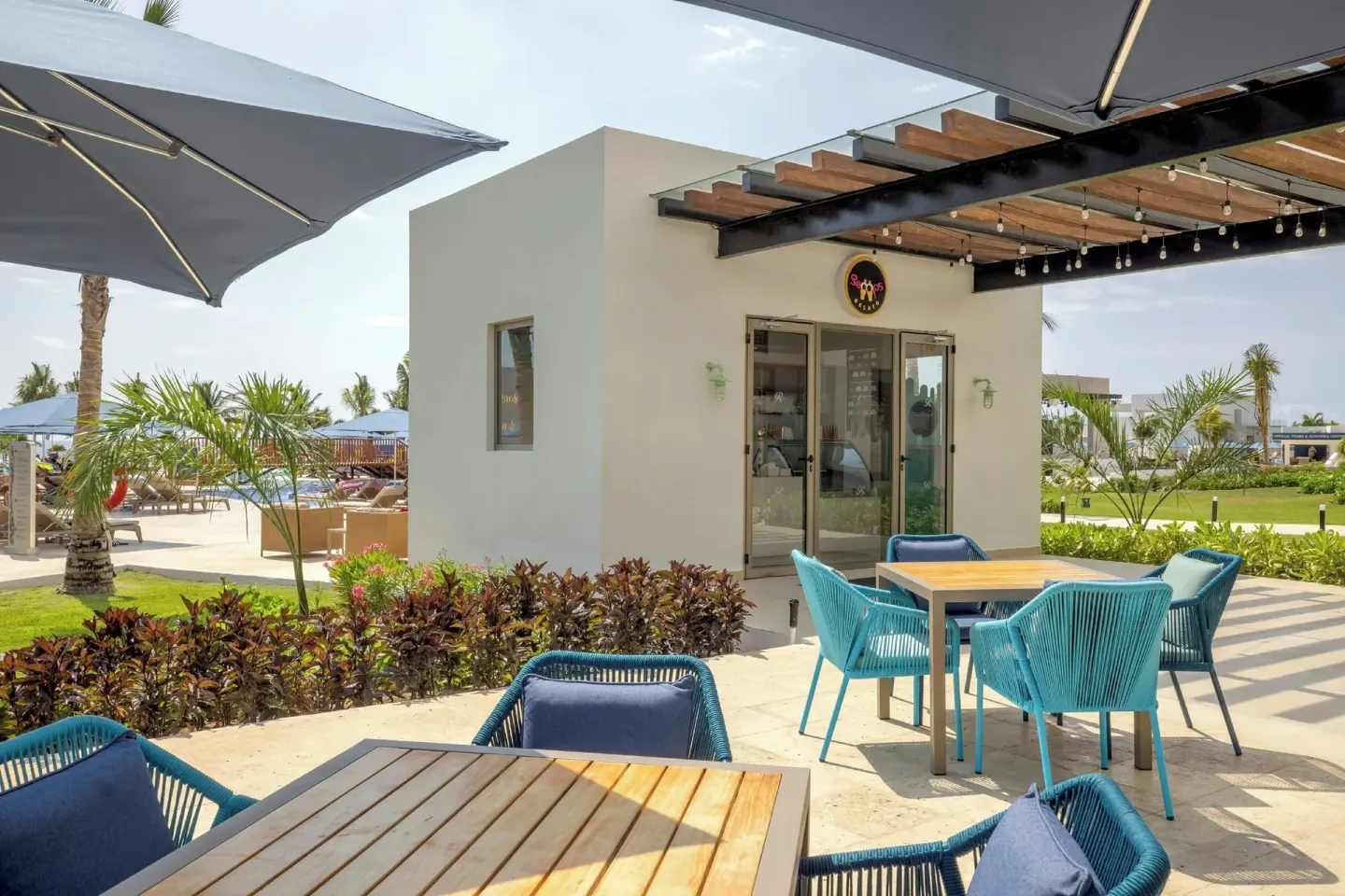 Scoops Gelato patio at Royalton Splash Riviera Cancun with blue chairs and shaded tables.