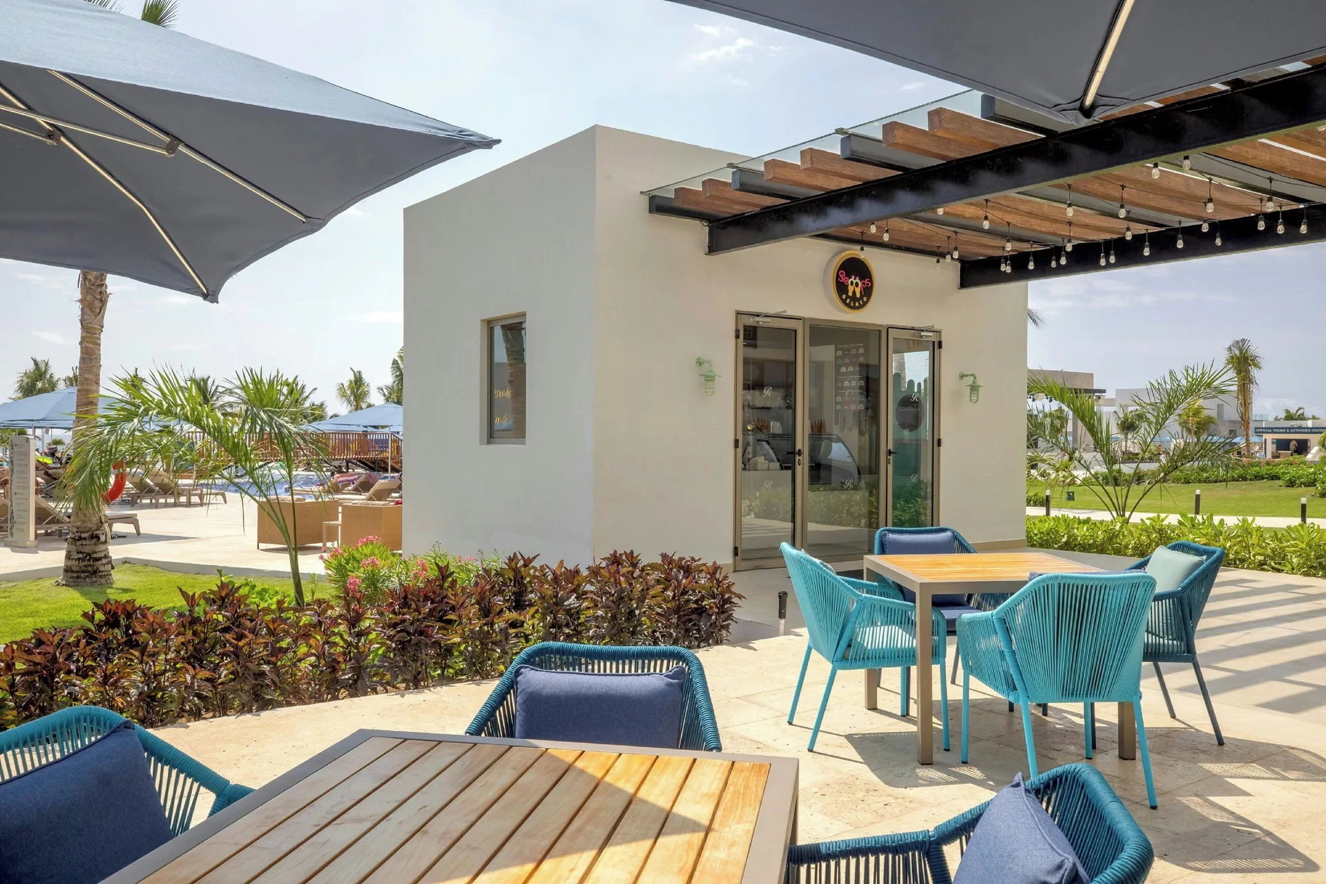 Scoops Gelato patio at Royalton Splash Riviera Cancun with blue chairs and shaded tables.