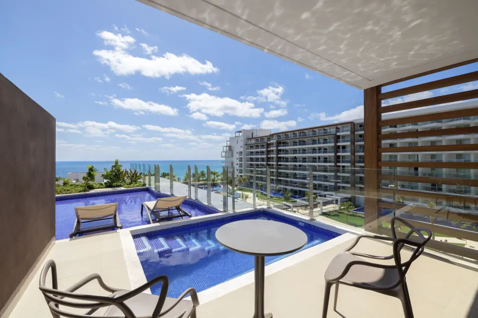 Covered swim-out terrace with table, chairs, and ocean view at Royalton Splash Riviera Cancun.