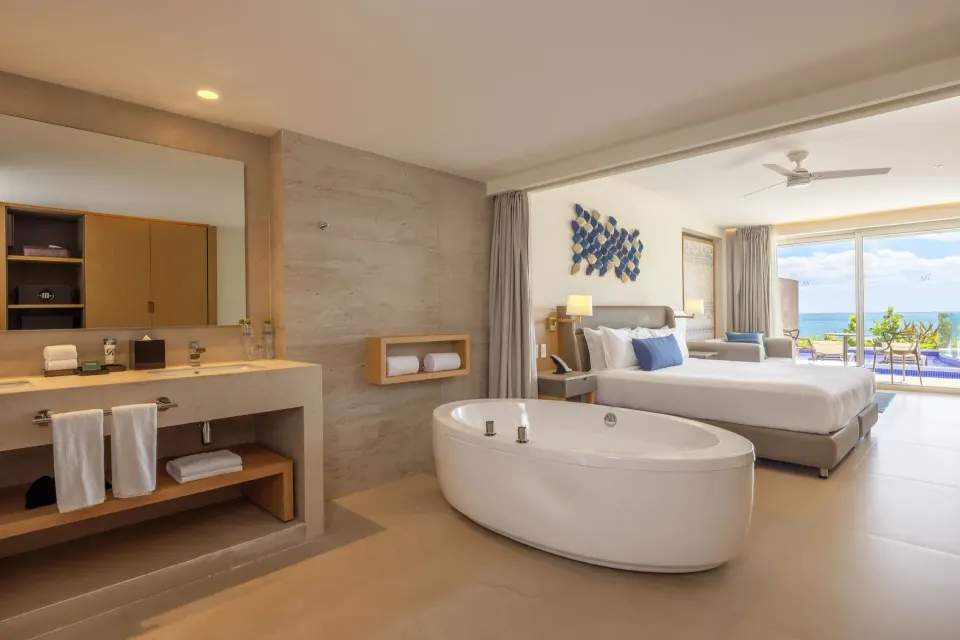 Open bath and king bed in an ocean front swim-out suite at Royalton Splash Riviera Cancun.