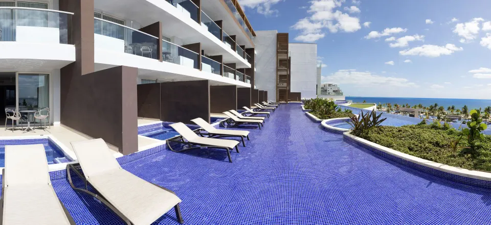 Swim-out suites with pool loungers and ocean beyond at Royalton Splash Riviera Cancun.