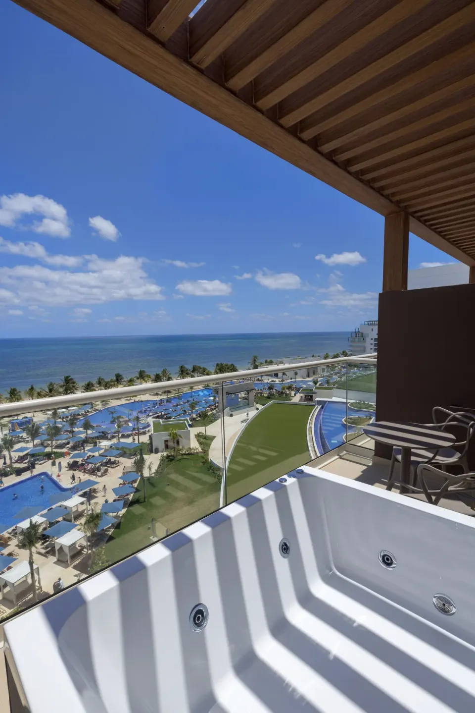 Oceanfront terrace Jacuzzi with resort pool view at Royalton Splash Riviera Cancun.