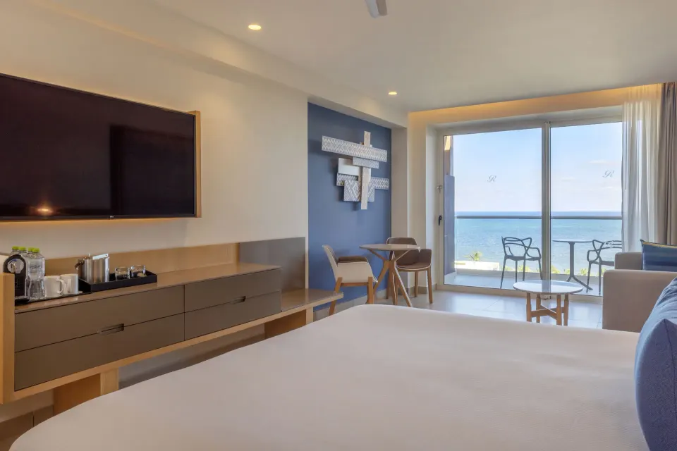 King bed and ocean-view balcony in a Luxury Junior Suite at Royalton Splash Riviera Cancun.