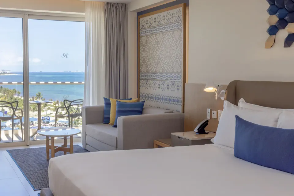 King bed and sofa facing an ocean-view balcony at Royalton Splash Riviera Cancun.