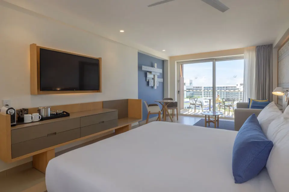 King bed, TV, sitting area, and balcony in a Luxury Junior Suite at Royalton Splash Riviera Cancun.