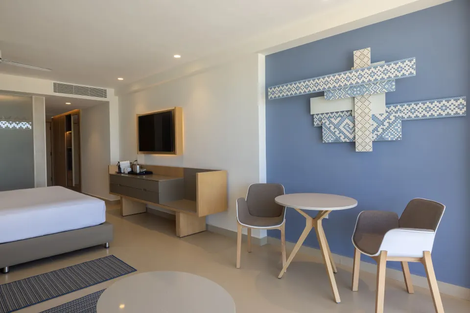 King bed, dining table, TV, and blue accent wall in a suite at Royalton Splash Riviera Cancun.