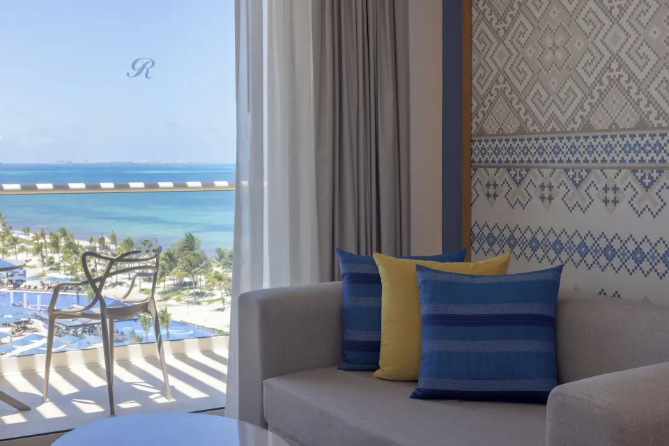 Sofa seating and balcony with ocean view in a Luxury Junior Suite at Royalton Splash Riviera Cancun.