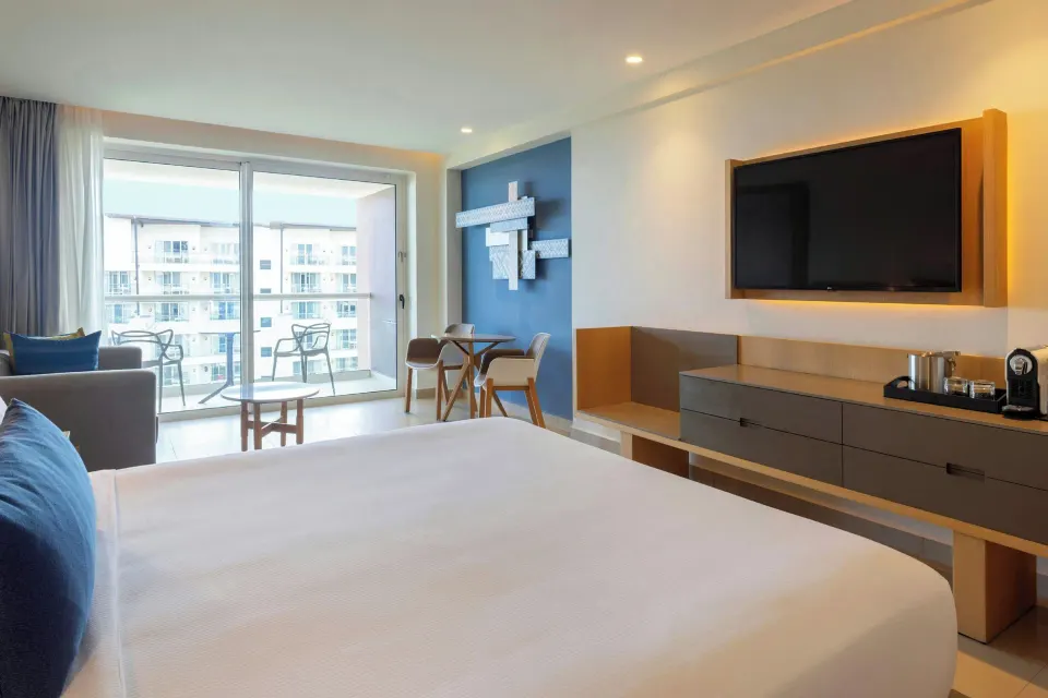 Luxury Junior Suite king bed with balcony and sitting area at Royalton Splash Riviera Cancun.