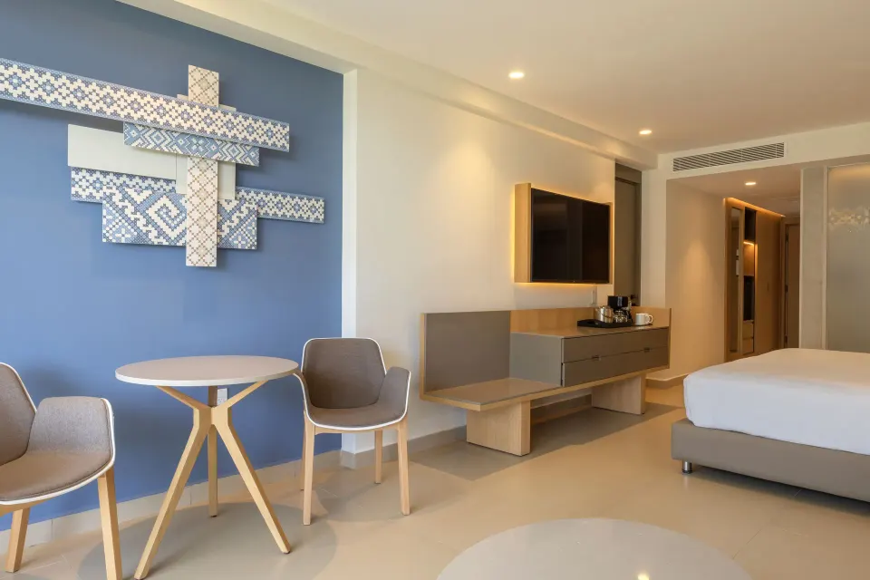 Luxury Junior Suite king bed, dining table and wall art at Royalton Splash Riviera Cancun.