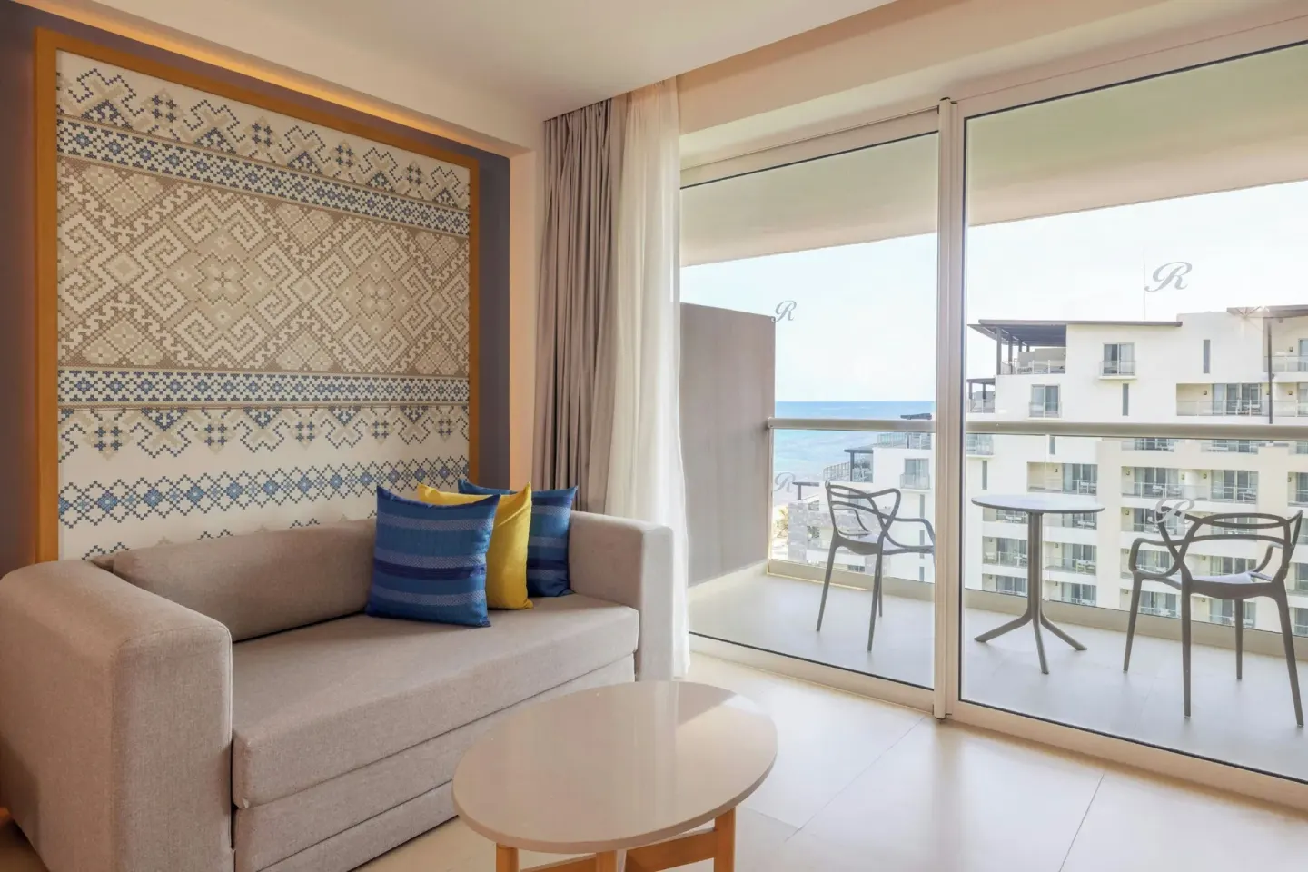 Luxury Junior Suite sofa and balcony with partial ocean view at Royalton Splash Riviera Cancun.