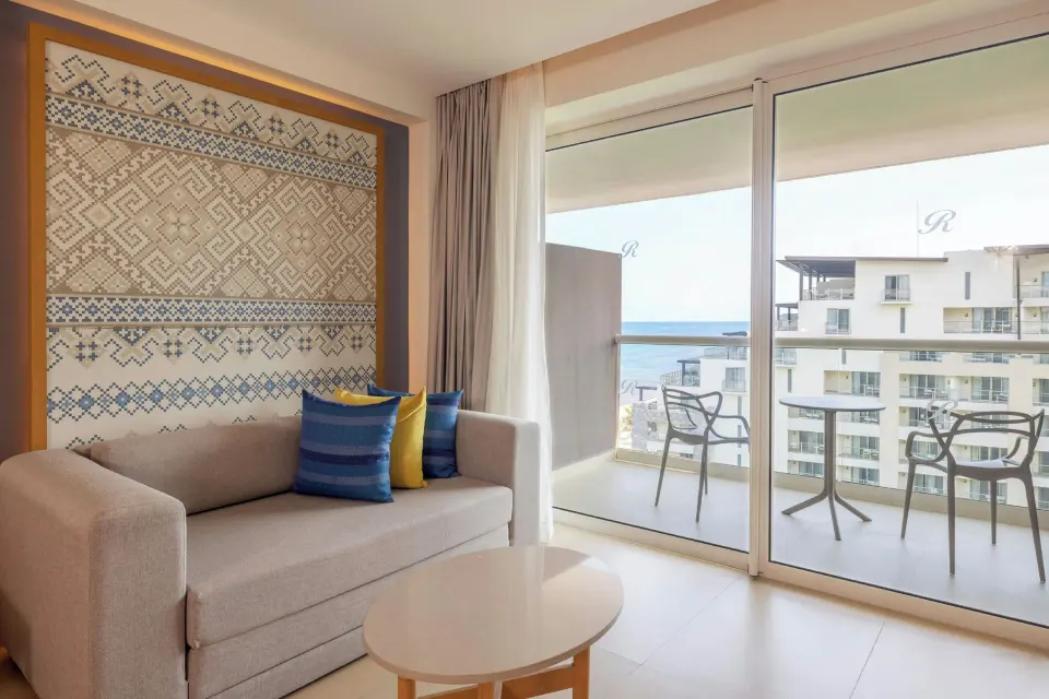Luxury Junior Suite sofa and balcony with partial ocean view at Royalton Splash Riviera Cancun.