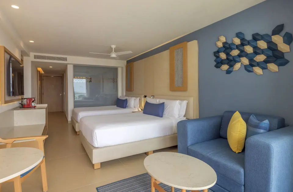 Two Bedroom Luxury Junior Suite with two beds and blue sofa at Royalton Splash Riviera Cancun.