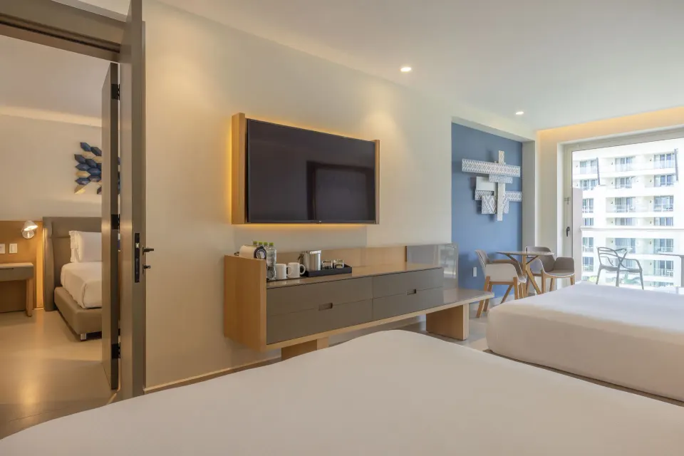 Two Bedroom Luxury Junior Suite with beds, TV and balcony at Royalton Splash Riviera Cancun.