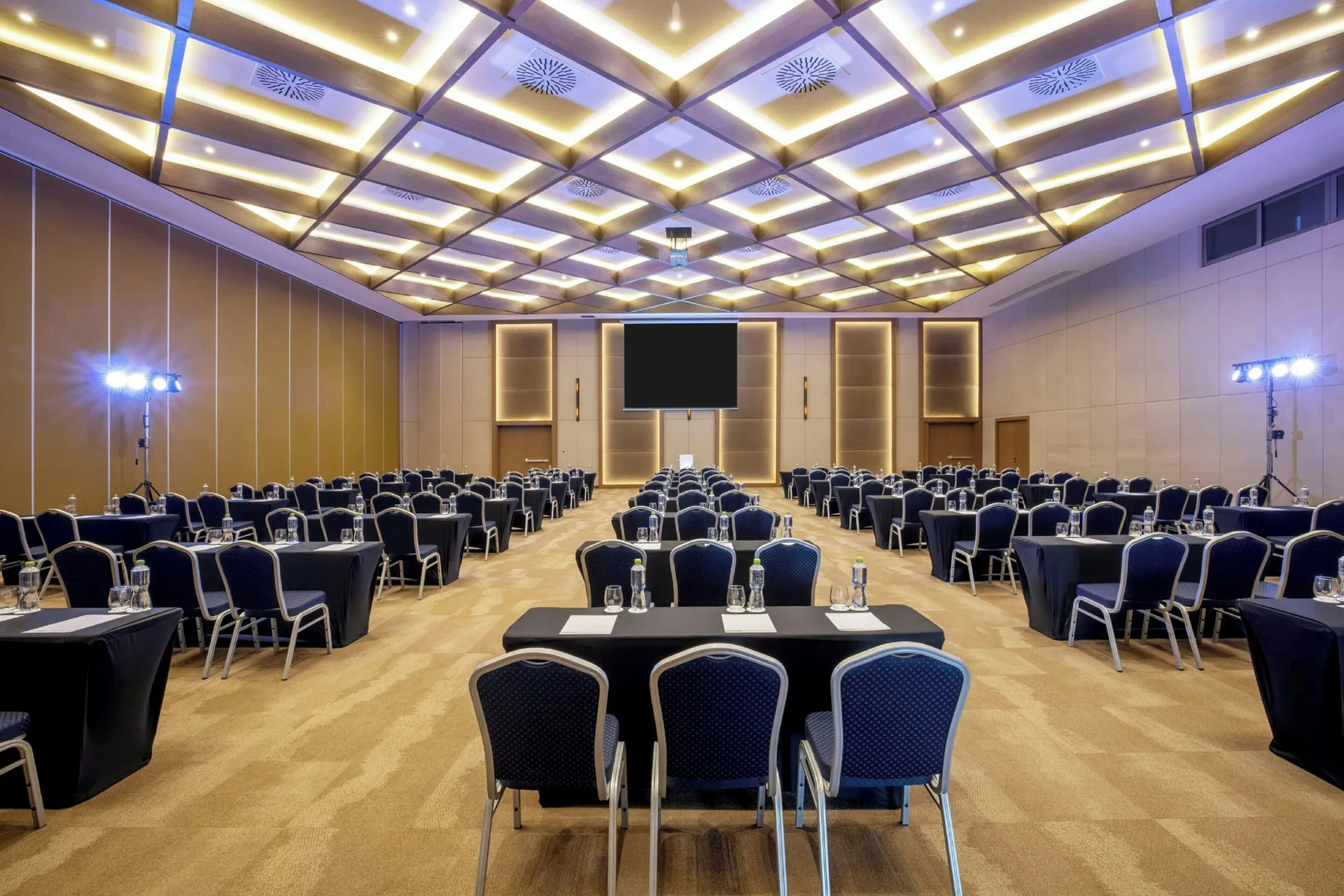 Meeting ballroom at Royalton Splash Riviera Cancun with round tables, blue chairs, and illuminated ceiling panels.