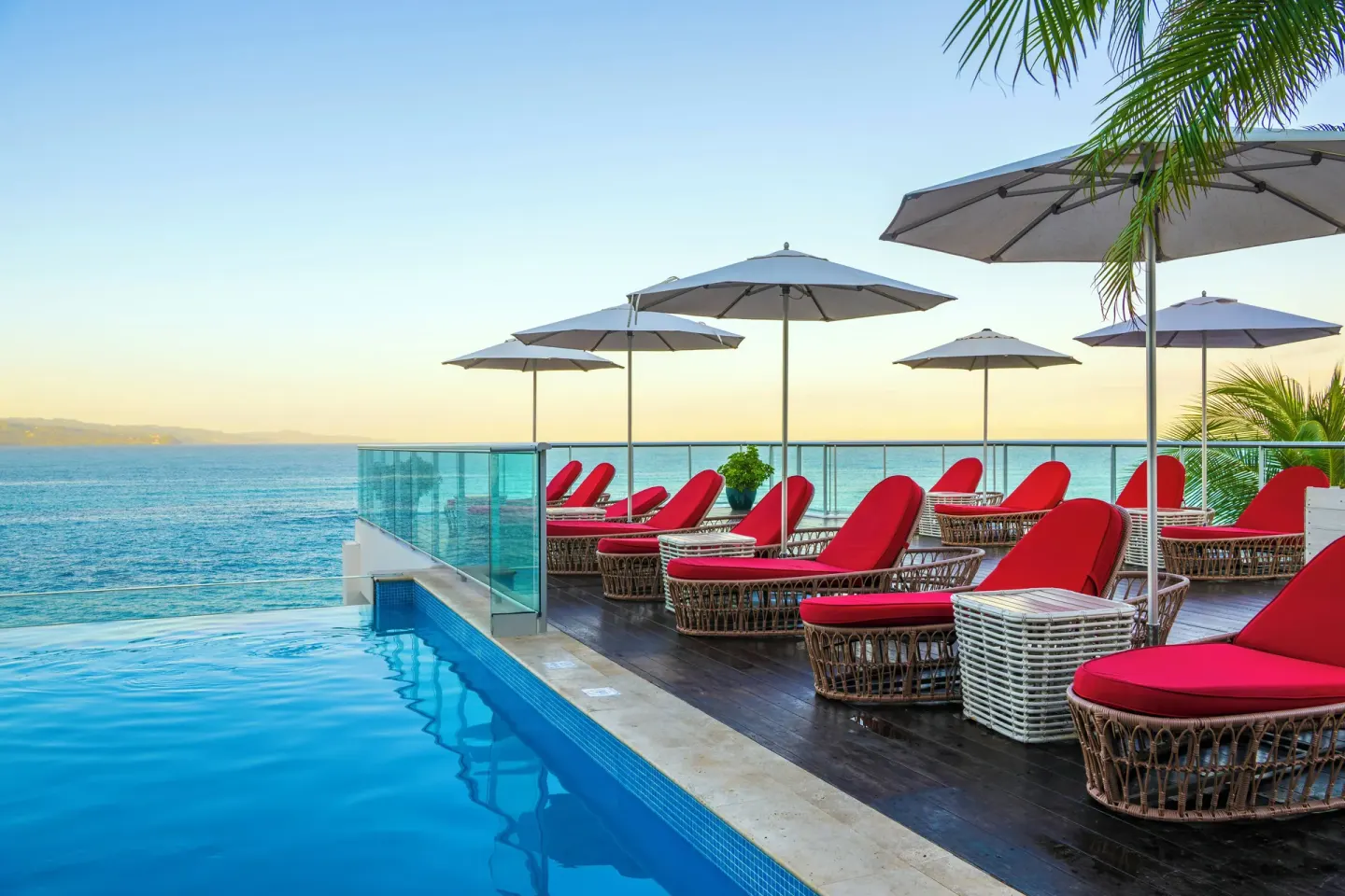 Infinity pool terrace with red loungers and ocean views at S Hotel Montego Bay.