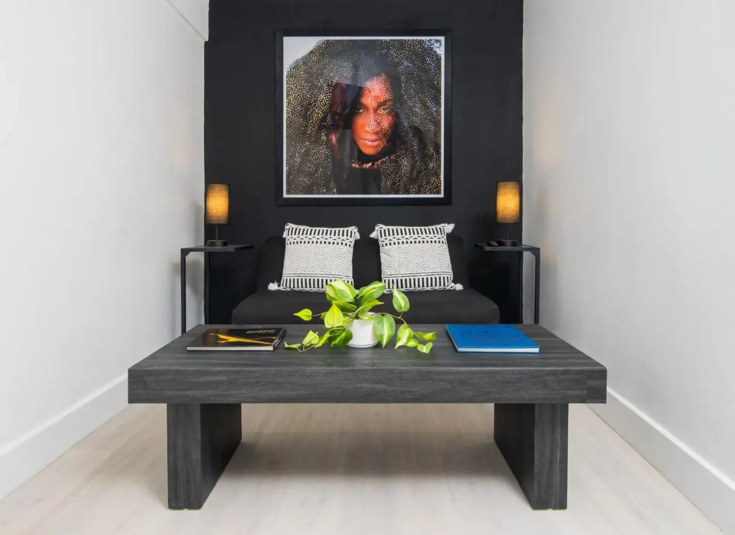 Lobby seating nook with black sofa, coffee table, plant, and portrait art at S Hotel Montego Bay.