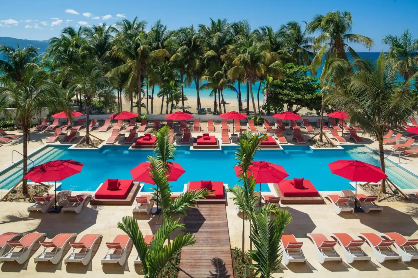 Main pool with red umbrellas and palm trees at S Hotel Montego Bay.