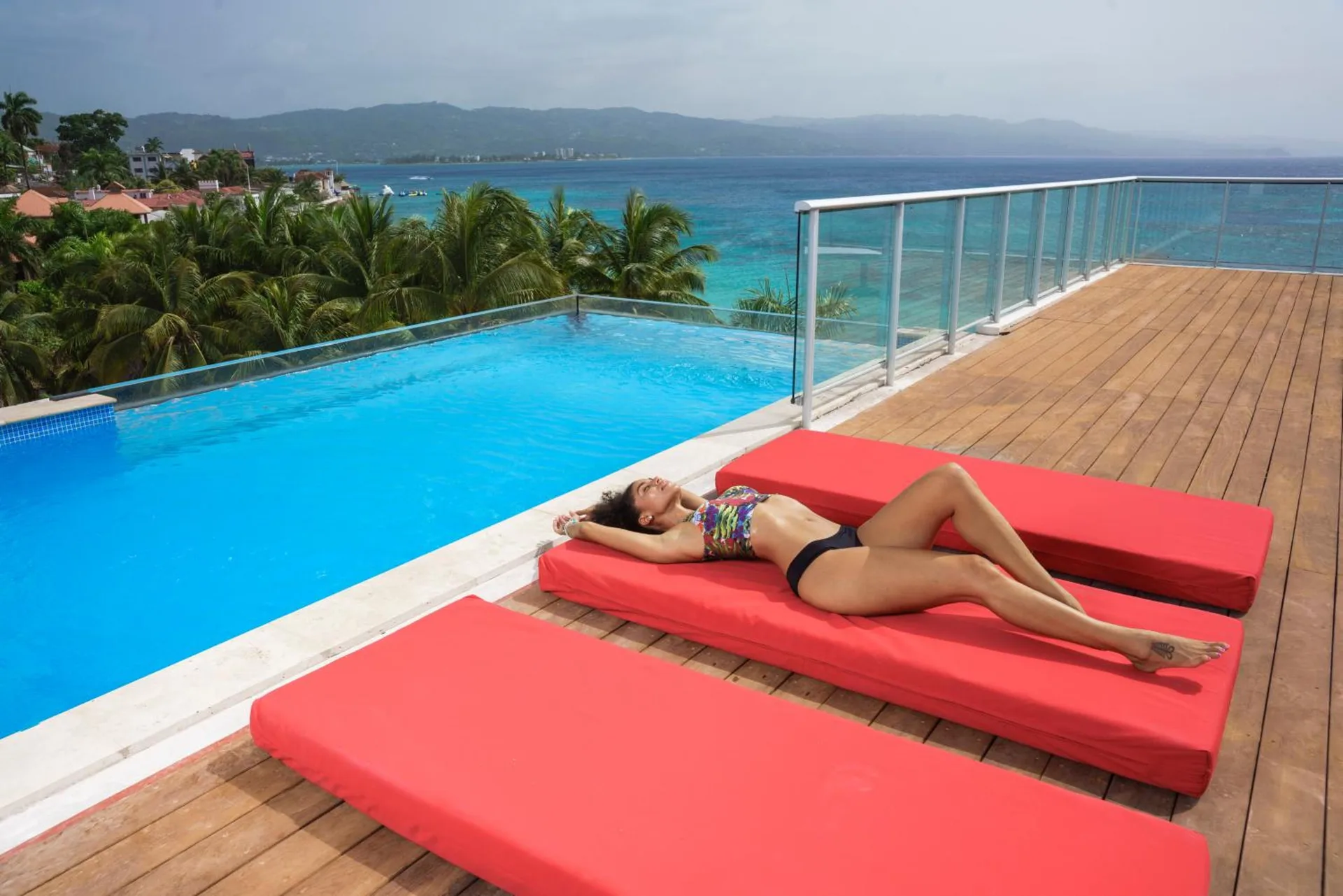 Rooftop pool deck with red loungers and ocean view at S Hotel Montego Bay.