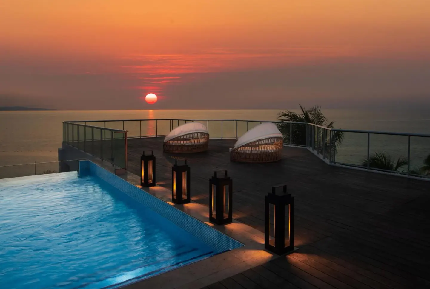 Pool deck with lanterns and sunset ocean view at S Hotel Montego Bay.