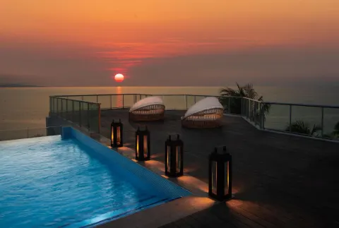 Pool deck with lanterns and sunset ocean view at S Hotel Montego Bay.