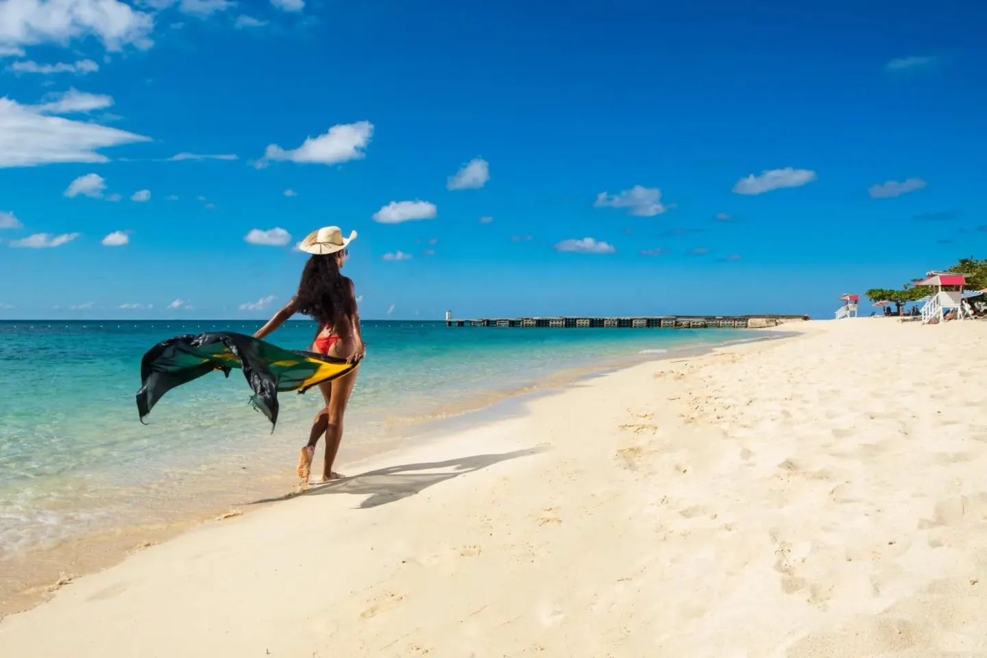 Woman walking along the turquoise beach at S Hotel Montego Bay.