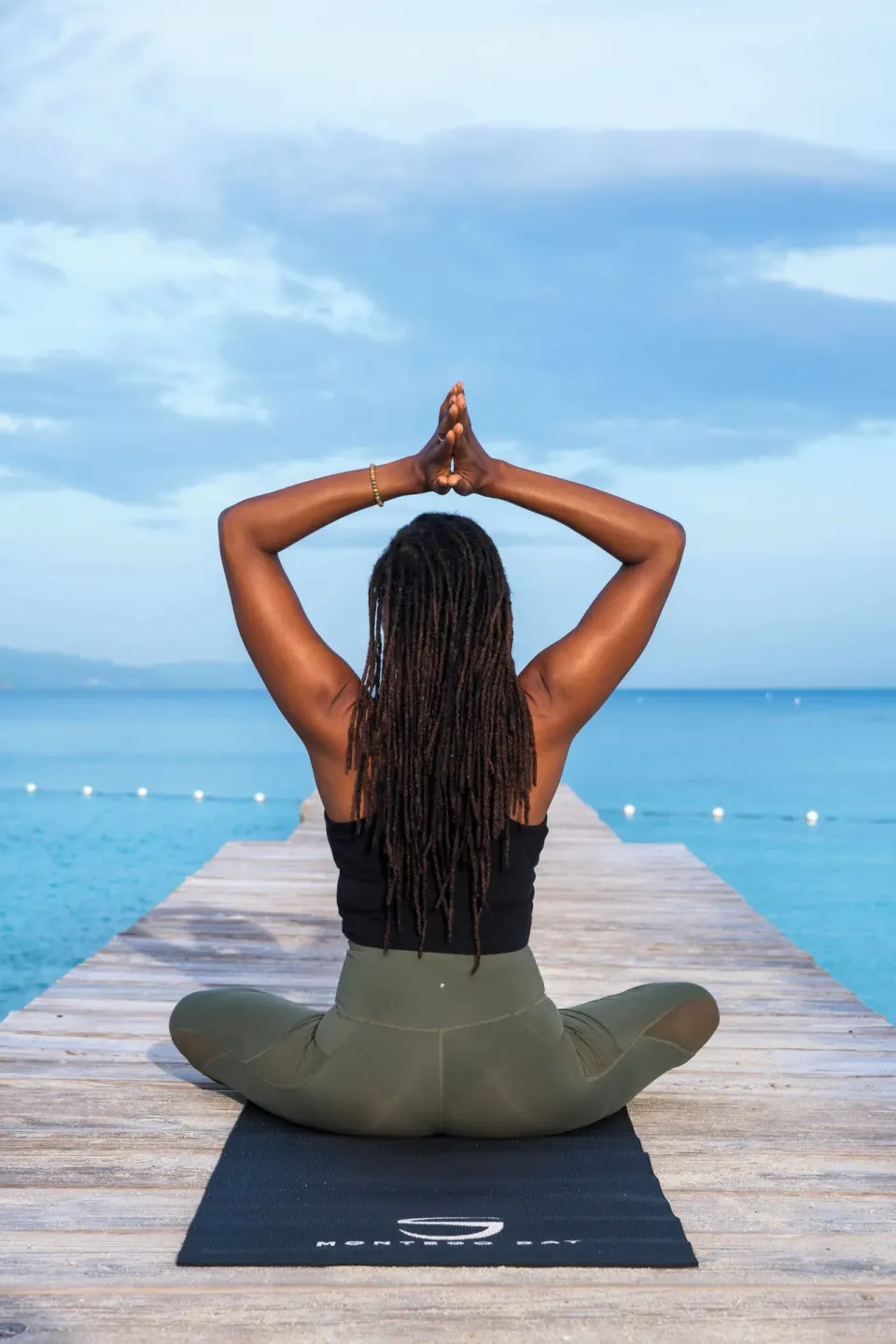 Guest seated in a yoga pose on a wooden pier over the sea at S Hotel Montego Bay.