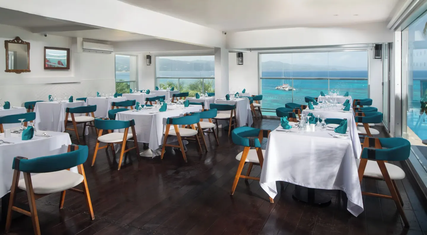 Oceanview dining room with teal chairs and set tables at S Hotel Montego Bay.