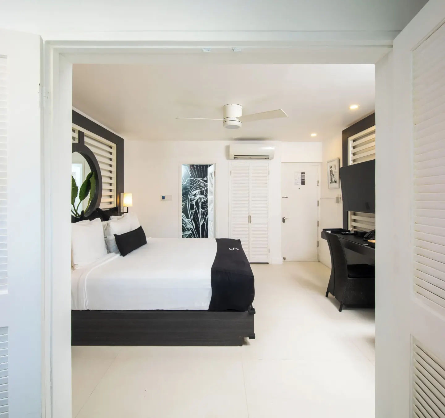 Mini Suite bedroom with king bed, desk and white shutters at S Hotel Montego Bay.