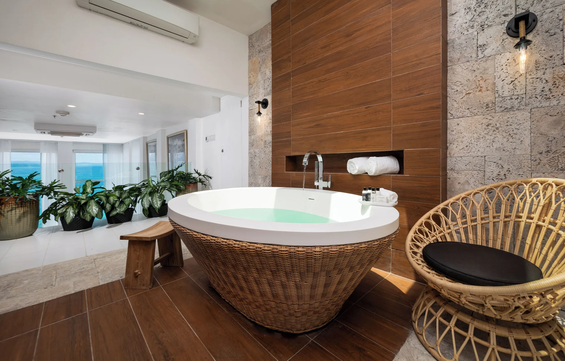 Presidential Suite bathroom with soaking tub and wicker chair at S Hotel Montego Bay.