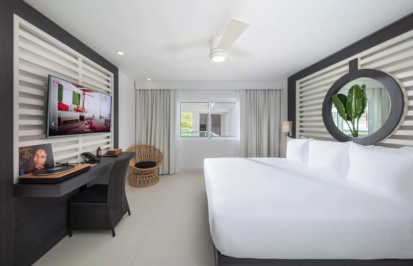 Mini Room with king bed, desk, TV and round mirror at S Hotel Montego Bay.