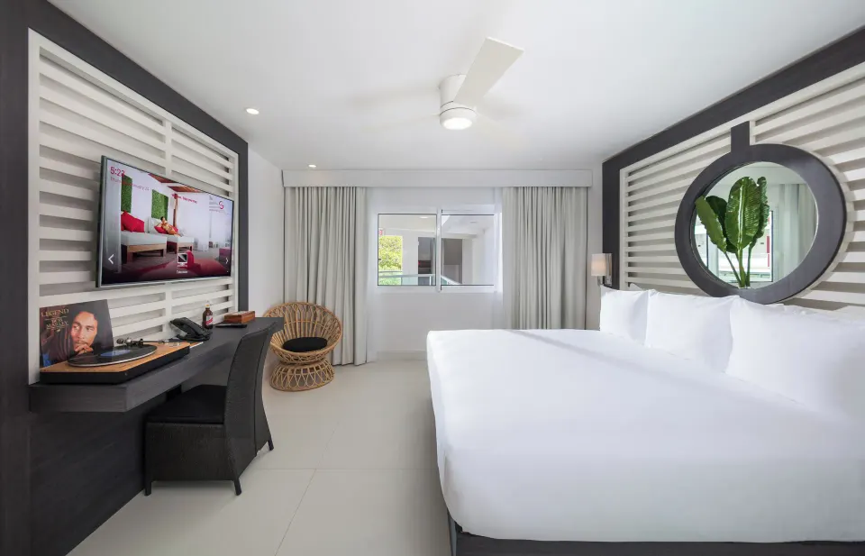 Mini Room with king bed, desk, TV and round mirror at S Hotel Montego Bay.