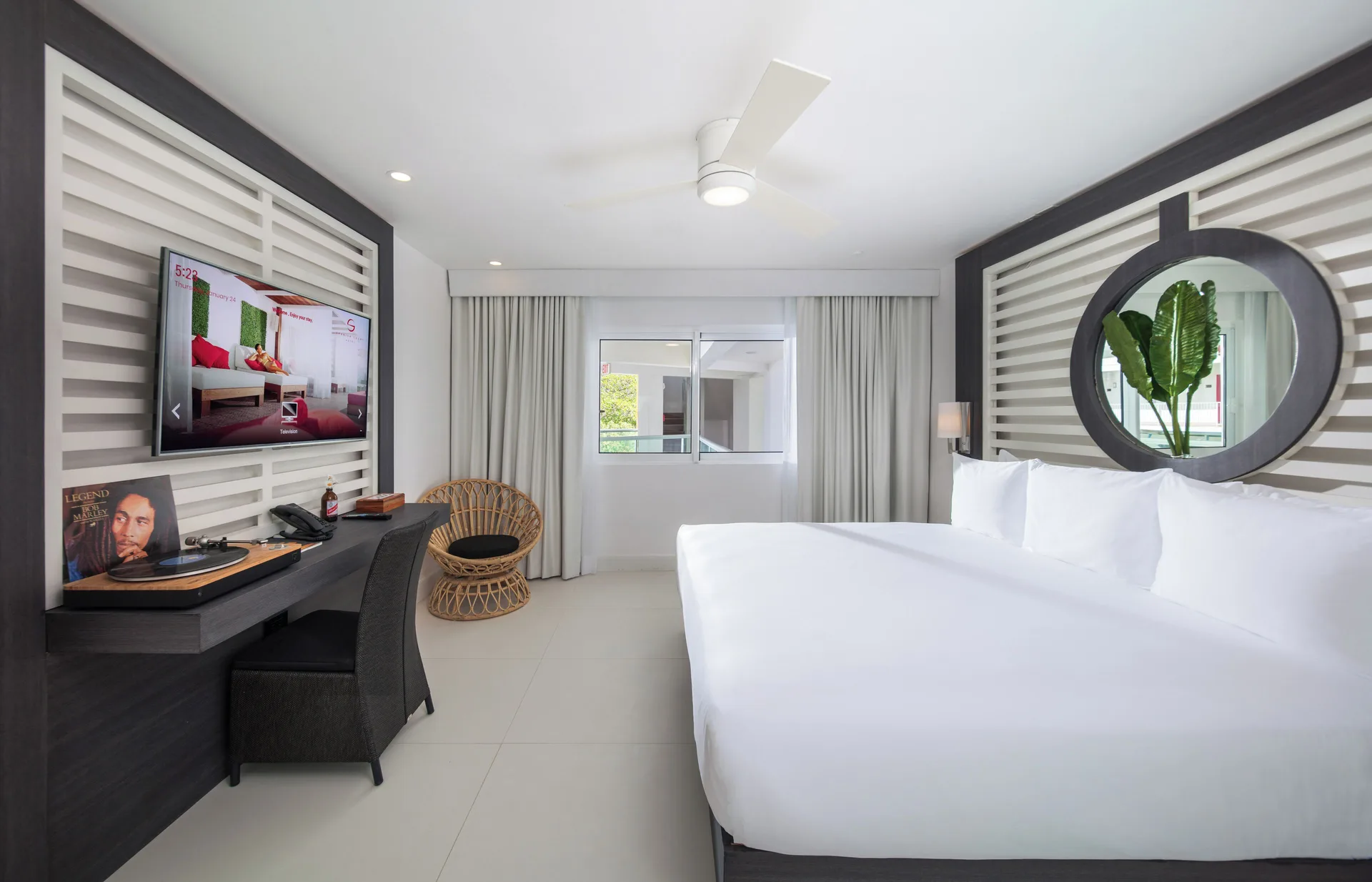 Mini Room with king bed, desk, TV and round mirror at S Hotel Montego Bay.