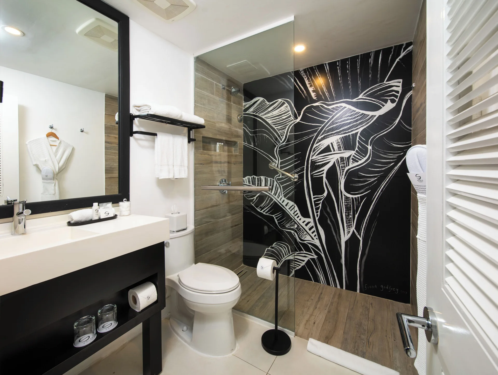 Mini Suite bathroom with glass shower, vanity, toilet, and leaf mural at S Hotel Montego Bay.